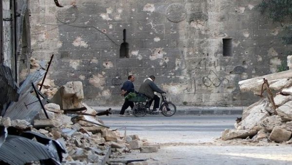 A man walks past a man riding a bicycle near the rubble of damaged buildings in the rebel held area of Old Aleppo, Syria November 14, 2016. 