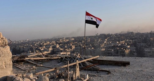 A Syrian national flag flutters near a general view of eastern Aleppo after Syrian government soldiers took control of al-Sakhour neigborhood in Aleppo.