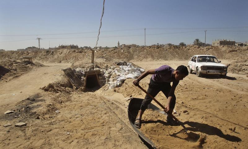 A worker shovels sand outside a tunnel on the border between Egypt and the southern Gaza Strip, Oct. 8, 2013.