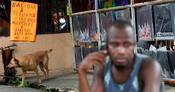 A placard is seen behind a Haitian migrant talking on a mobile in Tapachula, Chiapas, Mexico, Nov. 16, 2016.