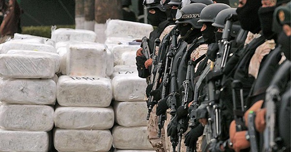 Mexican authorities stand guard beside seized narcotics.