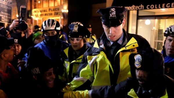 Police officers react as demonstrators against U.S. President-elect Donald Trump knock a police motorcycle on its side while the Deploraball is underway in Washington