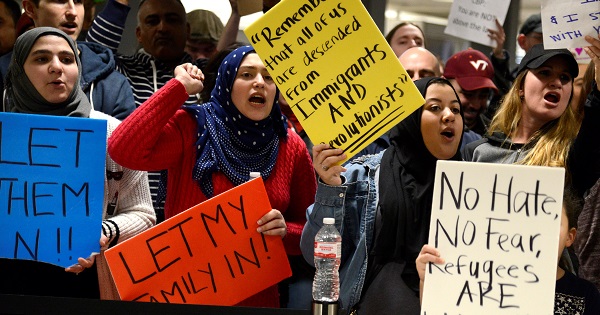 Dozens of pro-immigration demonstrators cheer and hold signs as international passengers arrive at Dulles International Airport in Chantilly, Virginia.