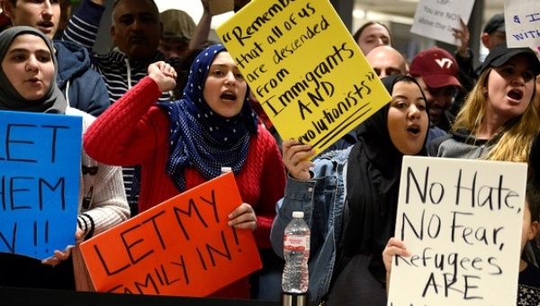 Dozens of pro-immigration demonstrators cheer and hold signs as international passengers arrive at Dulles International Airport in Chantilly, Virginia.