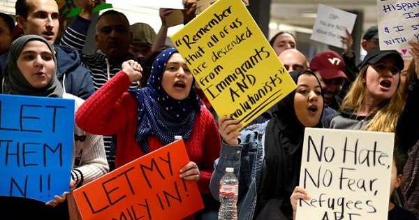 Dozens of pro-immigration demonstrators cheer and hold signs as international passengers arrive at Dulles International Airport.