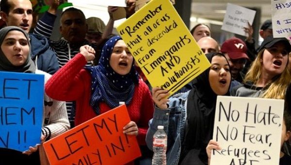 Dozens of pro-immigration demonstrators cheer and hold signs as international passengers arrive at Dulles International Airport.