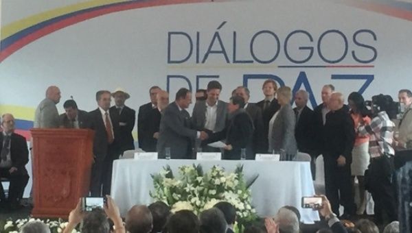 Lead negotiators from the ELN and the Colombian government shake hands.