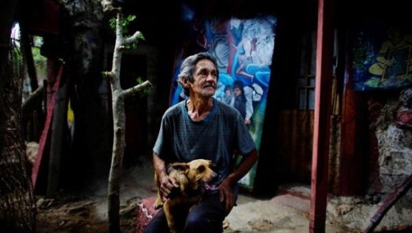 Artist Remigio Hernandez, 64, sits with his dog at his self made 'Museum of Baby' at his home in Moron, Cuba, Feb. 16, 2017.