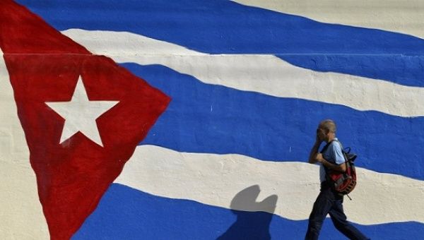 A man walks by a mural of the Cuban flag.