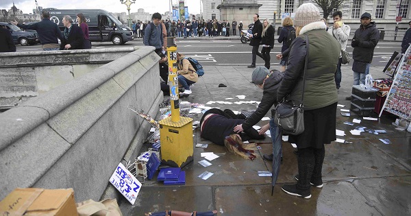 A woman assists an injured person after an incident on Westminster Bridge in London, March 22, 2017.