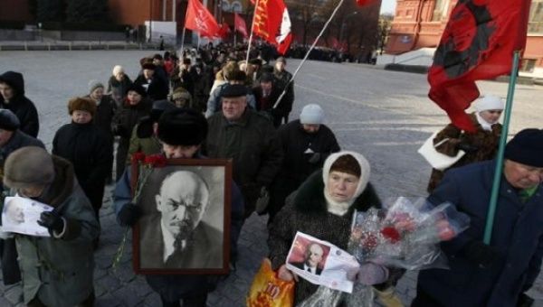Communist supporters hold flags and portraits of Soviet State founder Vladimir Lenin during a wreath laying ceremony at the Lenin's mausoleum on Moscow's Red Square Jan. 21, 2015. 