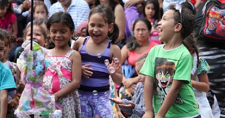 Children react to a puppet from which bubbles emanate.