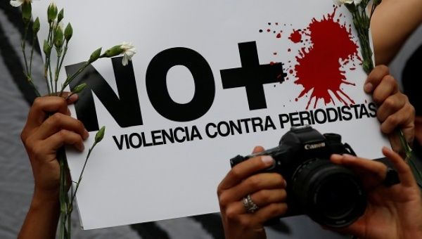 An activist holds a poster during a demonstration against journalist killings in Mexico at the Interior Ministry building in Mexico City.