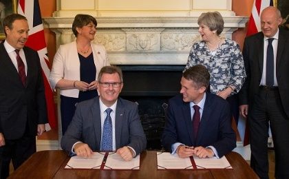 Prime Minister Theresa May next to DUP leader Arlene Foster, as DUP MP Jeffrey Donaldson signs paperwork with Britain's Parliamentary Secretary to the Treasury, Gavin Williamson.