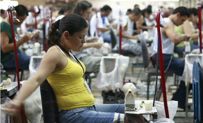 A factory worker stretches as she sews a baseball in Turrialba, Costa Rica.