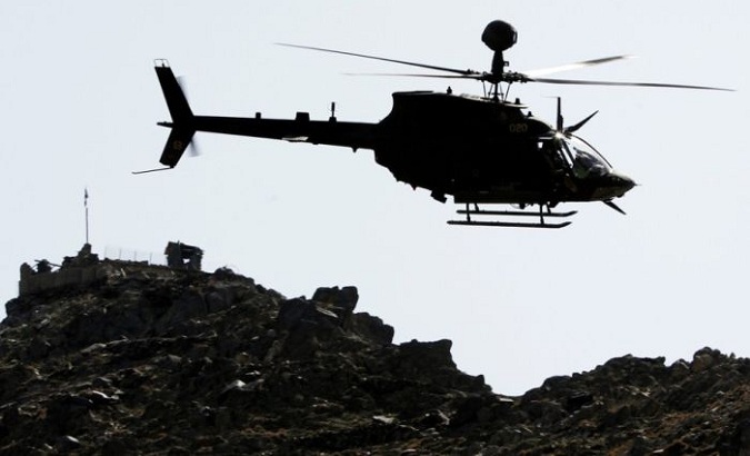 A U.S. military's Kiowa attack helicopter flies past an Afghan military combat outpost in Kunar province, eastern Afghanistan, on March 14, 2012.