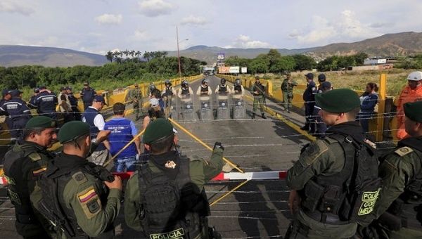 Colombian policemen stand guard in front of the border with Venezuelan policemen near Villa del Rosario village.