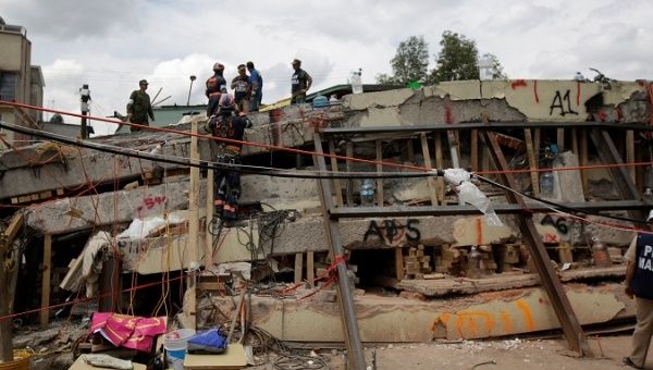 Members of a rescue team search for students amidst the rubble of a collapsed building of the Enrique Rebsamen school after an earthquake in Mexico City.