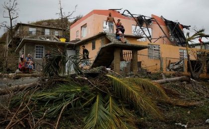 People rest outside a damaged house after the area was hit by Hurricane Maria in Yabucoa, Puerto Rico.