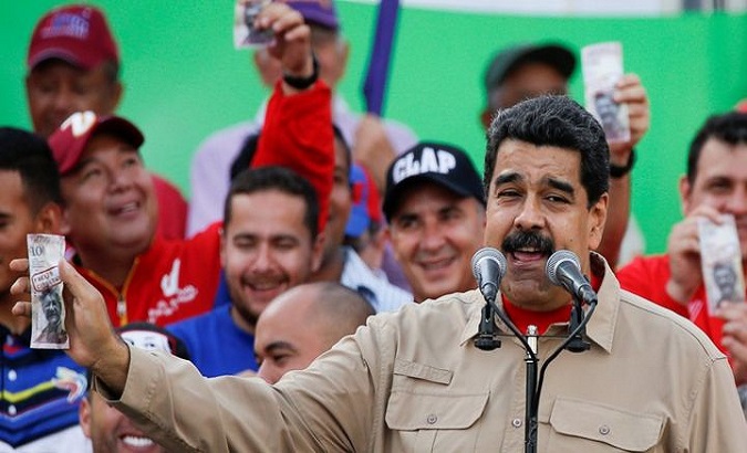 Venezuelan President Nicolas Maduro holds up a Venezuelan bolivar.
