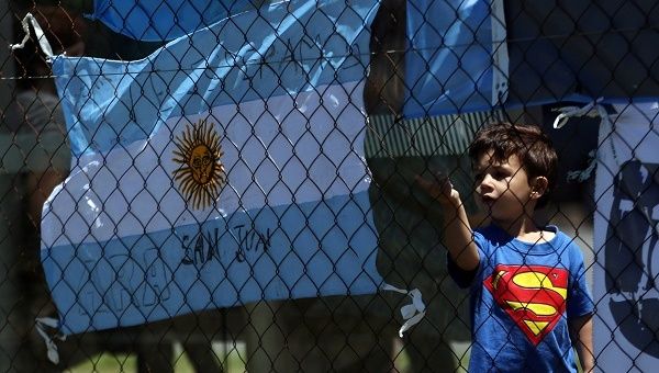 A boy stands next to an Argentine national flag with a message in support of the 44 crew members of the missing ARA San Juan submarine.