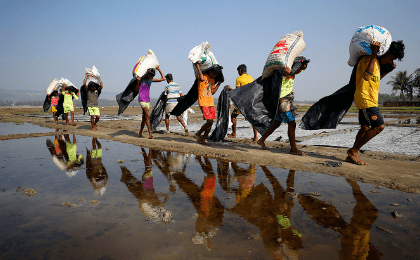 Rohingya refugee workers carrying bags of salt this month in a processing yard in Cox's Bazar, Bangladesh.