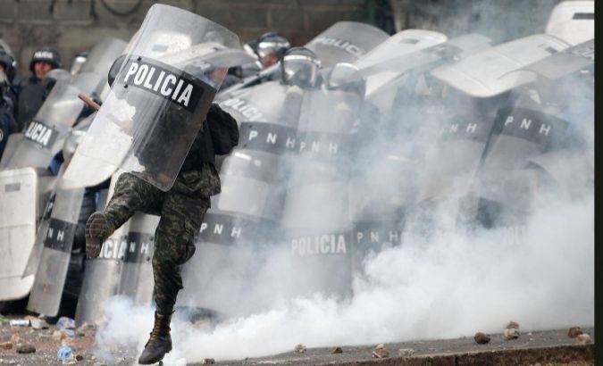 A Honduran soldier kicks a tear gas canister during a clash with protesters.