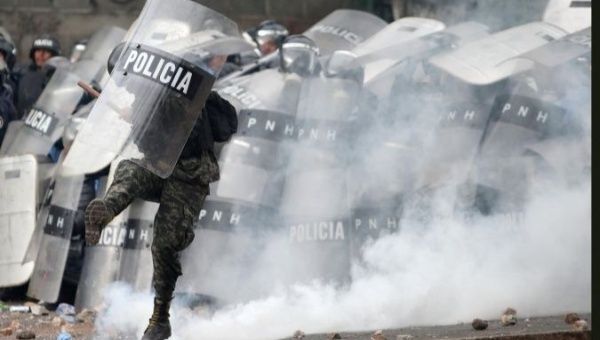 A Honduran soldier kicks a tear gas canister during a clash with protesters.