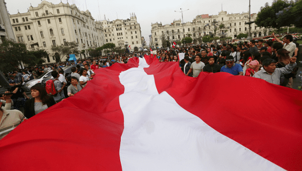 Protesters carry a giant Peruvian flag through the streets of Lima.