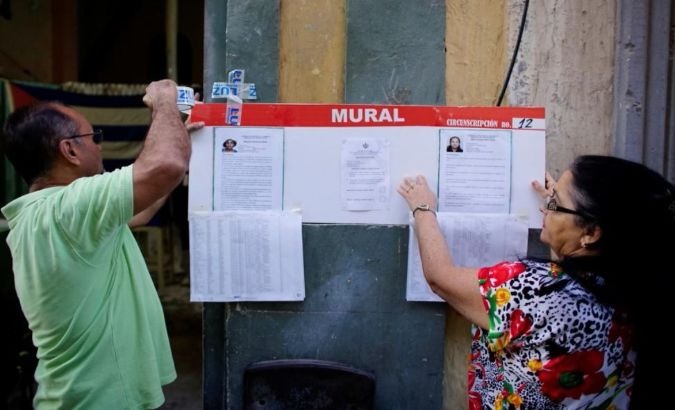 Election officials hang pictures and CVs of municipal assembly candidates moments before opening a polling station in Havana, Cuba on Nov. 26, 2017.