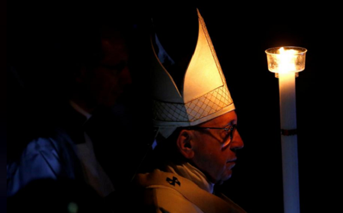Pope Francis holds a candle as he leads the Easter vigil mass in Saint Peter's Basilica at the Vatican, March 31, 2018.