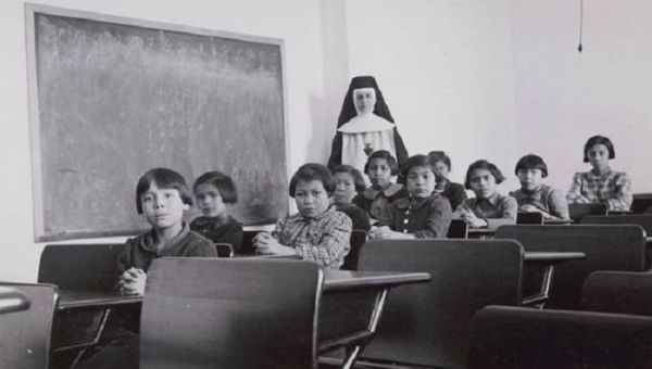 A group of female students and a nun pose in a classroom at Cross Lake Indian Residential School in Cross Lake, Mba., in a February, 1940. 