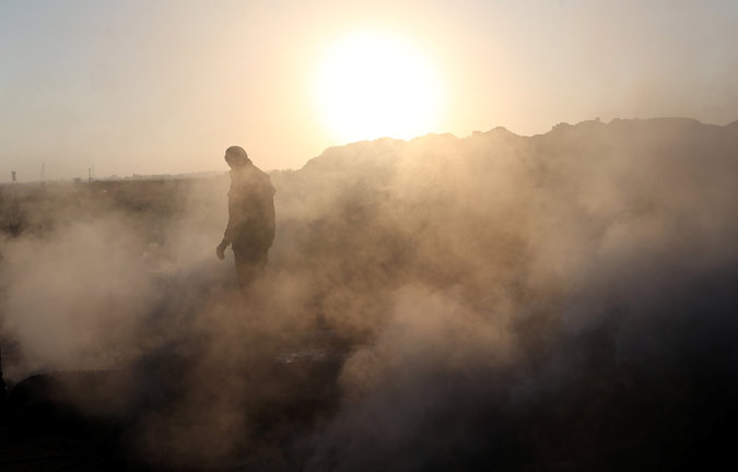 A Palestinian demonstrator is seen as smoke rises from a fire caused by objects dropped from Israeli drones