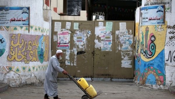 A Palestinian man pushes a cart past a closed school during a general strike in Khan Younis in the southern Gaza Strip Oct. 1, 2018.