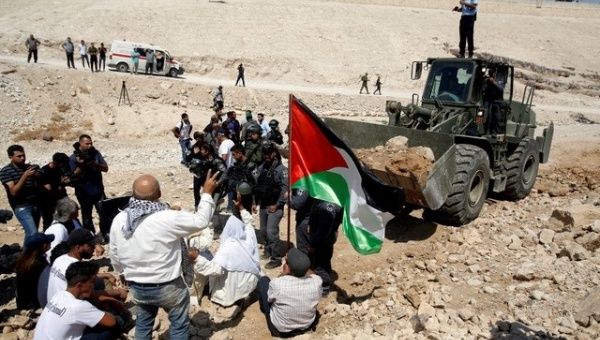 Palestinians protest in front of an Israeli bulldozer against Israel's plan to demolish the Palestinian Bedouin village of Khan al-Ahmar, Sept. 14, 2018. 