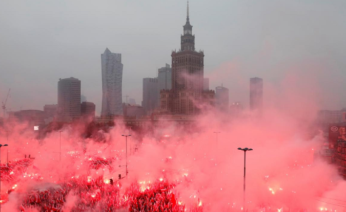 People carry Polish flags and flares as they sing Polish national anthem during a march marking the 100th anniversary of Polish independence in Warsaw, Poland November 11, 2018