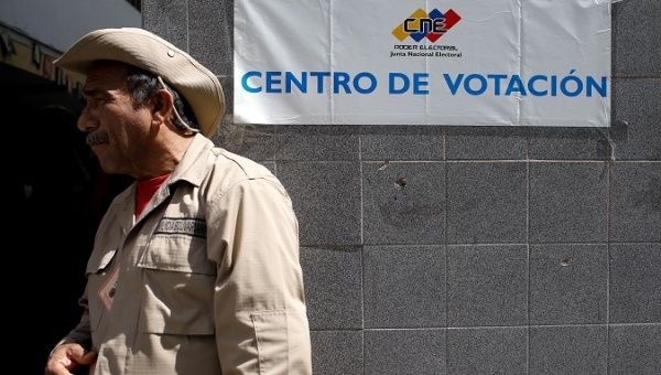 A militia member stands guard at a polling station during the municipal legislators election in Caracas