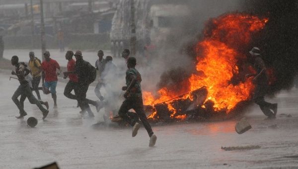 People run at a protest as barricades burn during rainfall in Harare, Zimbabwe Jan. 14, 2019. 