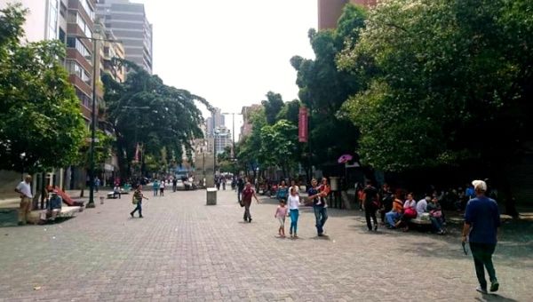 Venezuelans go on their daily activities on Plaza Venezuela in Caracas March 8 at midday