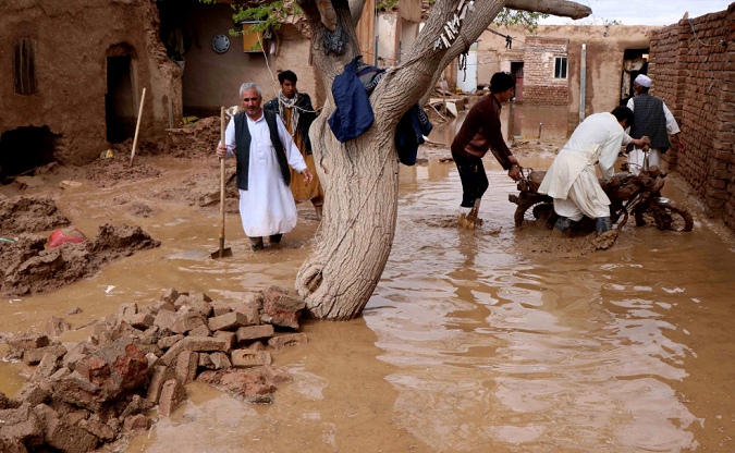 People wading through flood waters in Herat province, Afghanistan March 29, 2019.