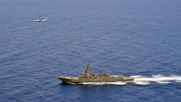 A P-8A Poseidon attached to Maritime Patrol Squadron (VP) 8 flies over the guided-missile destroyer USS Momsen (DDG 92) in the South China Sea