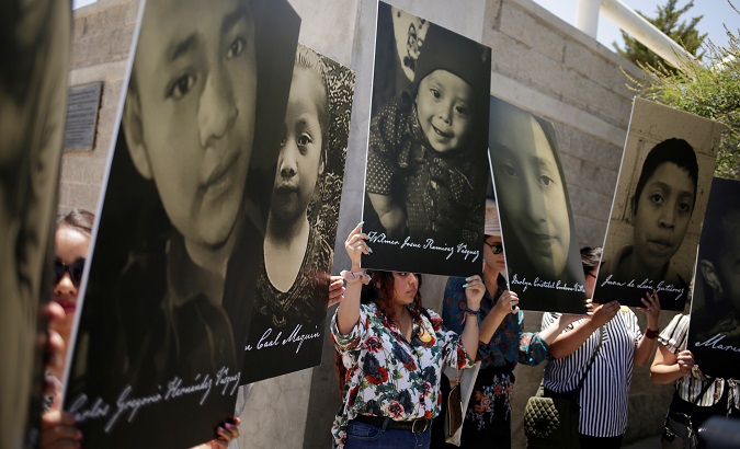 Human rights defenders holding photos of migrant children who died in U.S. custody protest protest at the Paso del Norte international border bridge, June 27, 2019.