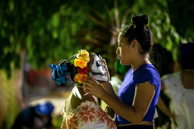 Woman paints the face of a teenage girl who is getting ready to the Hanal Pixan celebration in Lerona Vicario town, Quintana Roo, Mexico, Oct. 31, 2019.