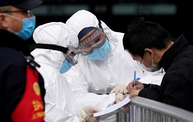 Staff members wearing protective masks check a passenger at Shanghai railway station in Shanghai, China, as the country is hit by an outbreak of a new coronavirus, February 2, 2020.