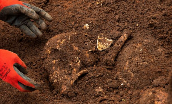 A Burundian worker from the Truth and Reconciliation Commission extracts the skull of an unidentified person from a mass grave in the Bukirasazi hill in Karusi Province, Burundi January 27, 2020.