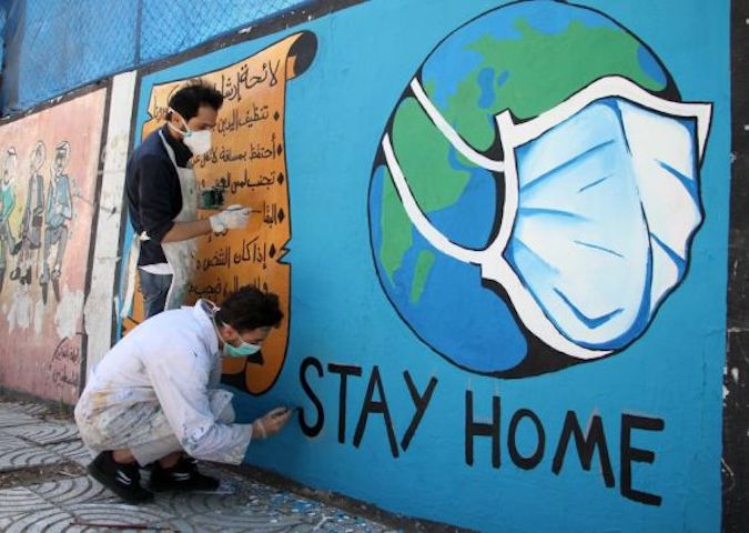 Palestinian artists draw a mural in the form of a globe wearing a protective mask, during awareness campaign to prevent the spread of COVID-19 coronavirus, in Gaza city, on April 2, 2020.