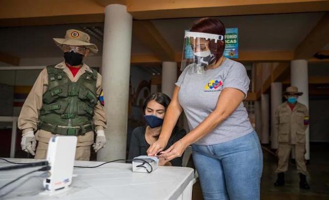 Staff from the National Electoral Council (CNE) assist a person during the institution's permanent registration in Caracas, Venezuela, July 22, 2020.