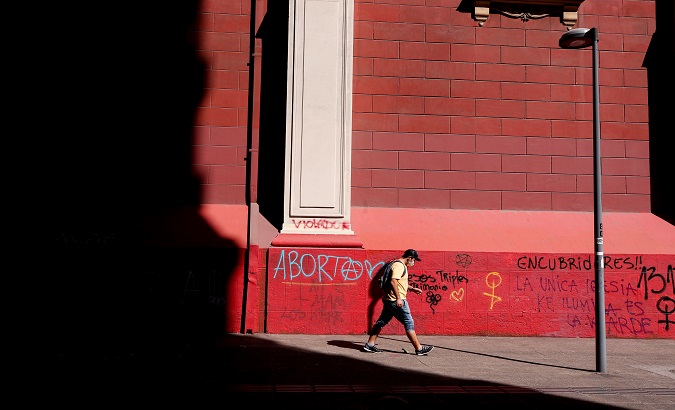 A man walks near a wall with graffiti calling for the legalization of abortion. Santiago de Chile, Chile. March, 2020.