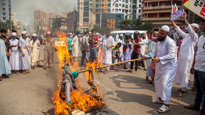 Members of the Islami Andolan Bangladesh party burn an image of French President Emmanuel Macron as they take part in a march towards the French Embassy in Dhaka, Bangladesh, October 27, 2020.