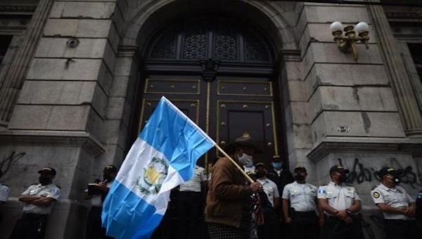 A man holds a Guatemalan flag in front of the Congress, Guatemala City, Guatemala, Nov. 24, 2020.